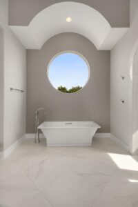 Square shaped bathtub under circular window in luxury bathroom