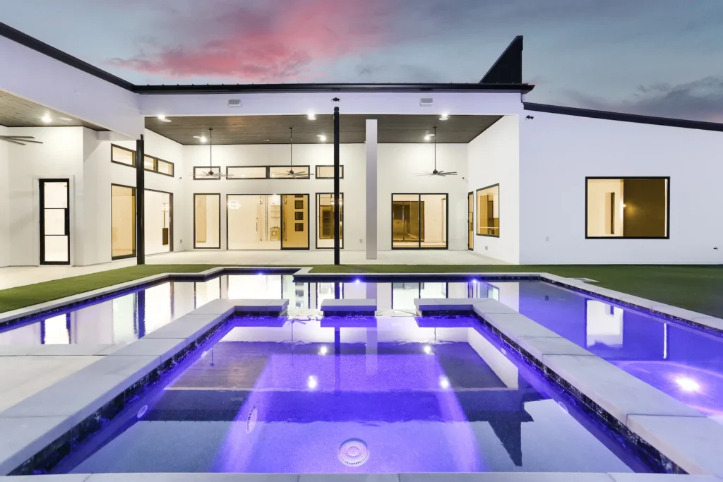 Hot tub and swimming pool with purple lights in backyard of custom home in Cantera Hills.