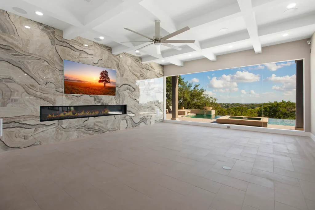 Contemporary living room with wall to wall windows providing view of swimming pool.